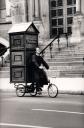 Father Anthony (aka Joey Skaggs) pedals Portofess, his portable confessional booth